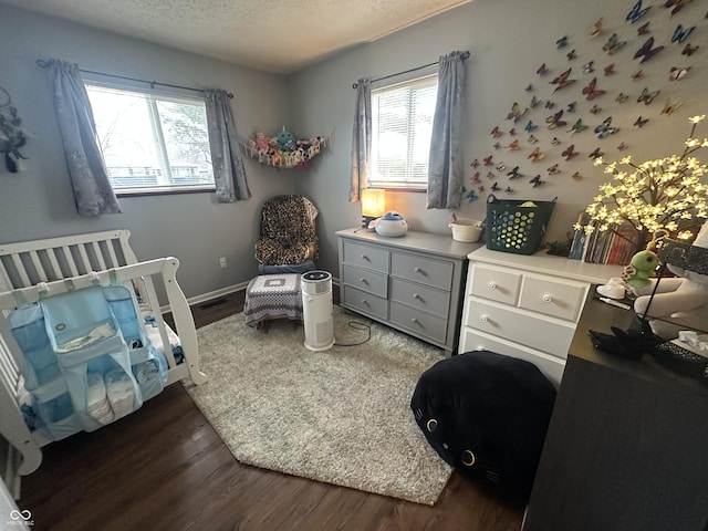 bedroom with dark wood-style floors, baseboards, and a textured ceiling