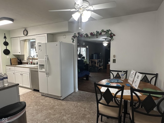 kitchen featuring dishwasher, white fridge with ice dispenser, a sink, and white cabinetry