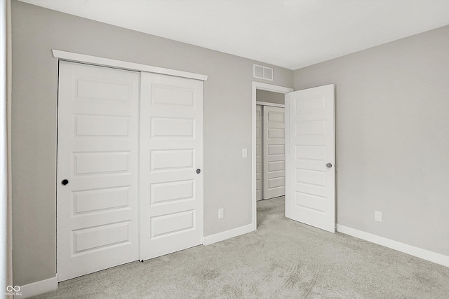 unfurnished bedroom with light colored carpet and a closet