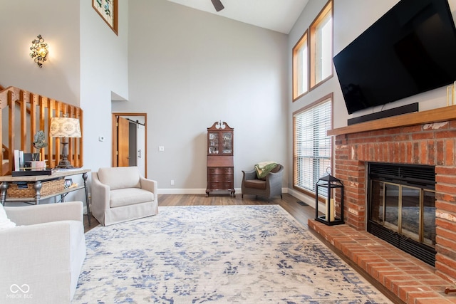 living room featuring wood-type flooring, high vaulted ceiling, ceiling fan, and a fireplace