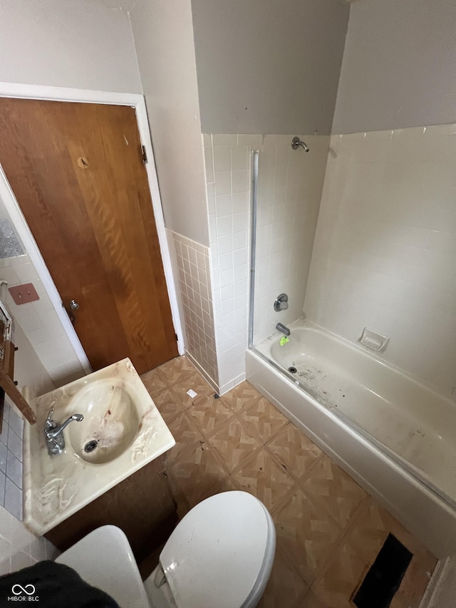 full bathroom featuring tile walls, vanity, toilet, and washtub / shower combination