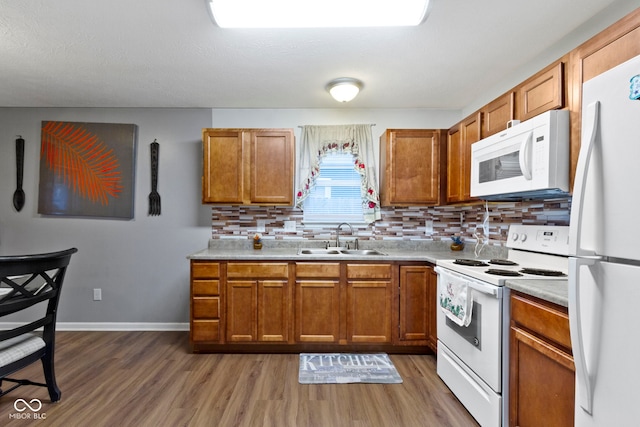 kitchen featuring sink, dark wood-type flooring, backsplash, and white appliances