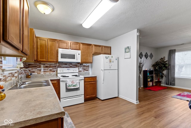 kitchen featuring sink, decorative backsplash, white appliances, and light hardwood / wood-style flooring