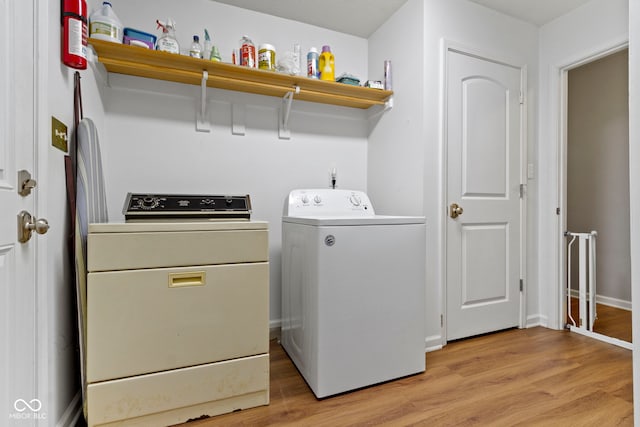 laundry area featuring washing machine and clothes dryer and light hardwood / wood-style floors