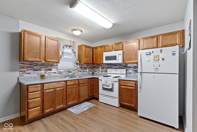 kitchen with tasteful backsplash, sink, white appliances, and light hardwood / wood-style flooring