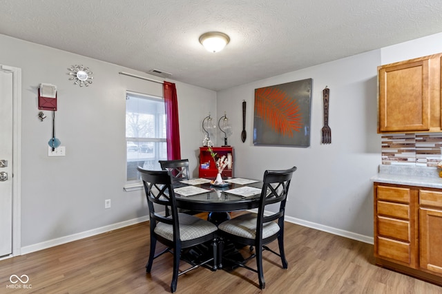 dining area featuring light hardwood / wood-style flooring and a textured ceiling