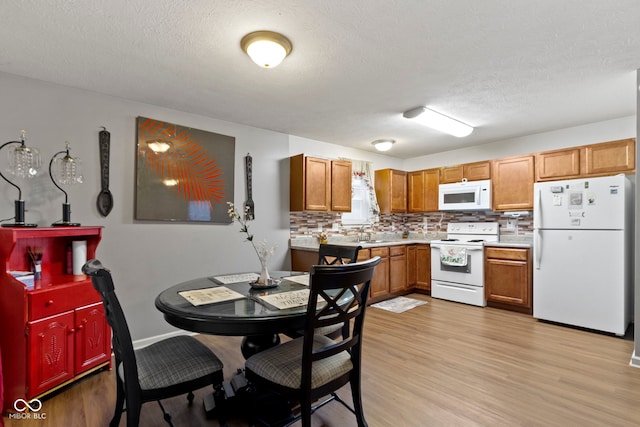 kitchen featuring tasteful backsplash, sink, white appliances, and light wood-type flooring