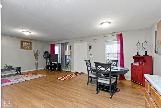 dining room featuring light hardwood / wood-style flooring and a textured ceiling