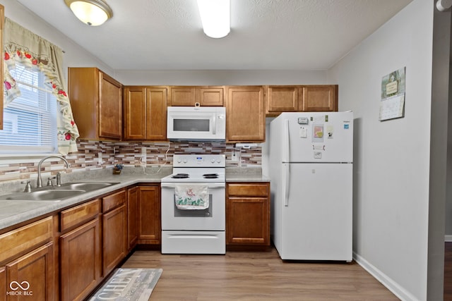 kitchen featuring sink, a textured ceiling, light hardwood / wood-style flooring, white appliances, and decorative backsplash