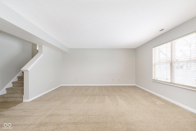 spare room with light carpet, stairs, and baseboards