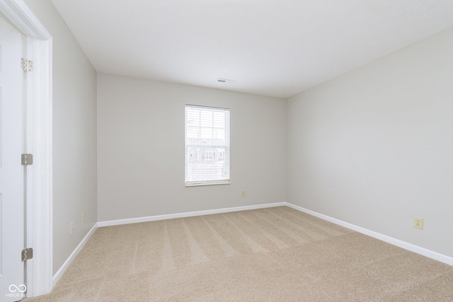 empty room featuring light colored carpet and baseboards