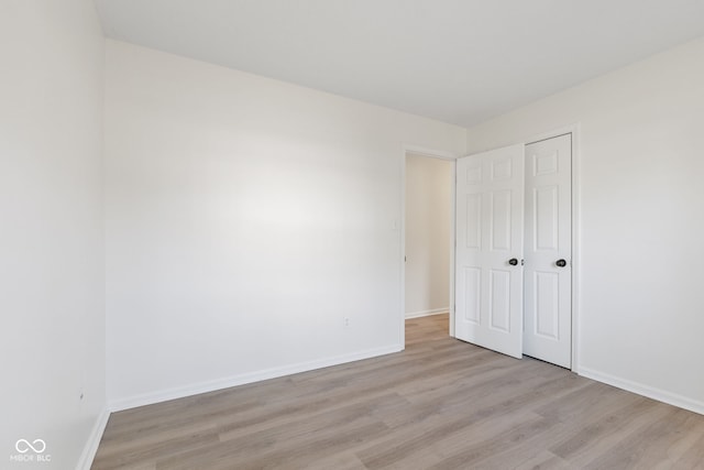 unfurnished bedroom with light wood finished floors, a closet, and baseboards