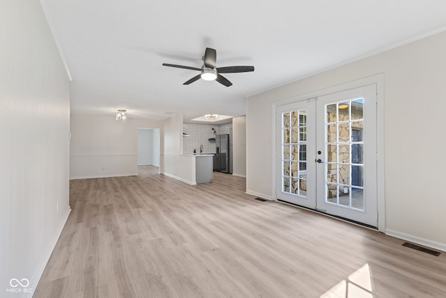 unfurnished living room with a ceiling fan, french doors, visible vents, and light wood finished floors