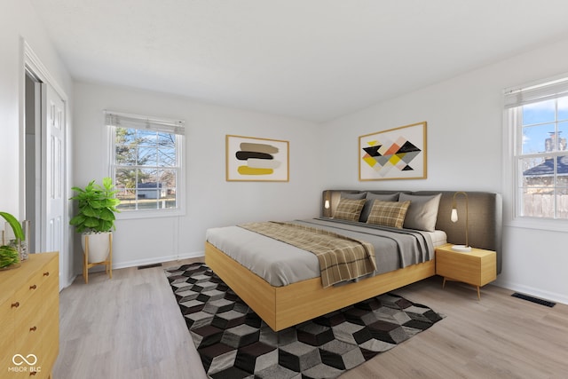 bedroom featuring a closet, visible vents, light wood-style flooring, and baseboards