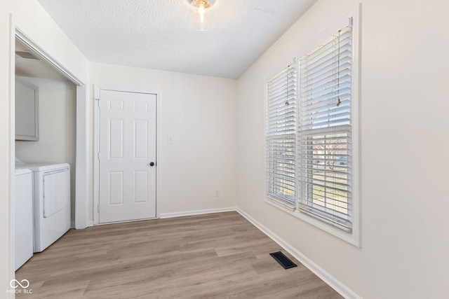 spare room featuring washer and dryer, light wood-style flooring, and a healthy amount of sunlight