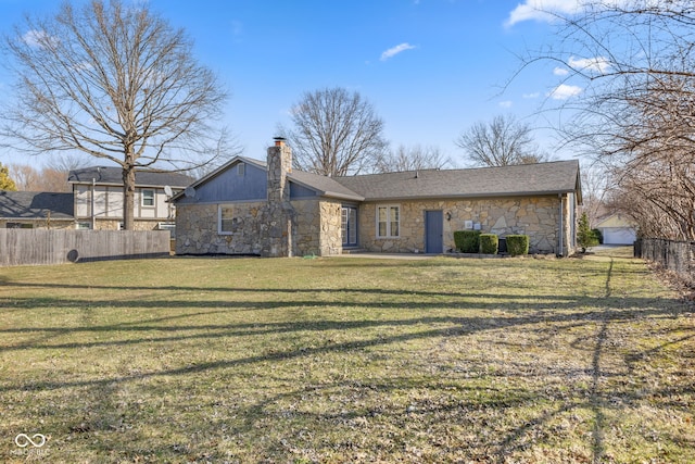 back of house with fence, a lawn, stone siding, and a chimney