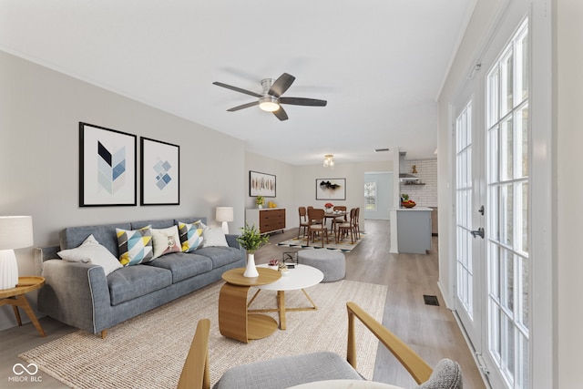 living area with visible vents, a ceiling fan, and light wood-style floors