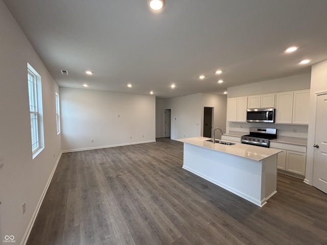 kitchen featuring baseboards, dark wood finished floors, a sink, white cabinets, and appliances with stainless steel finishes