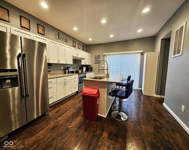 kitchen featuring light stone countertops, appliances with stainless steel finishes, an island with sink, and a kitchen breakfast bar