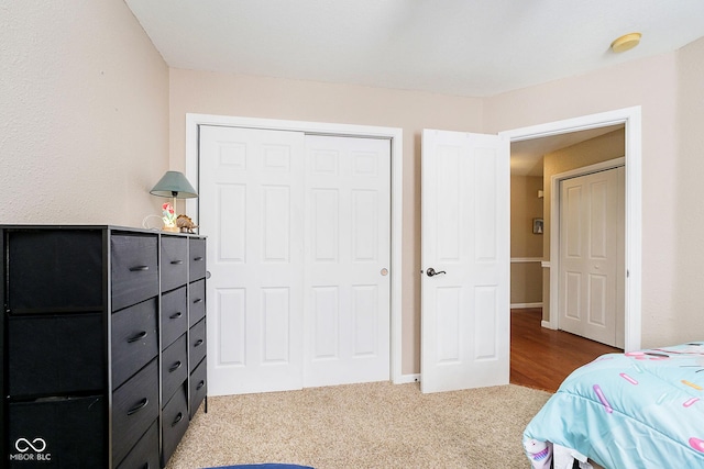 bedroom with baseboards, a closet, and light colored carpet