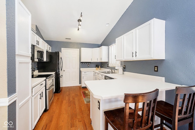 kitchen featuring range with two ovens, a breakfast bar area, a peninsula, white cabinetry, and light countertops