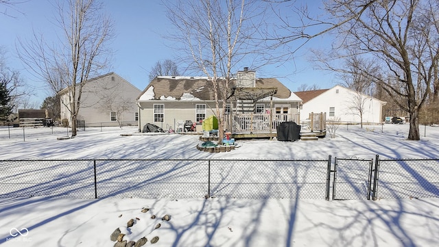 snow covered rear of property with a chimney, fence, and a deck