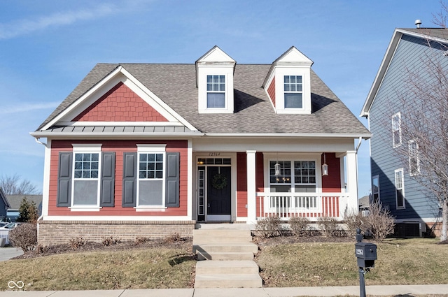 view of front of property featuring a porch, cooling unit, roof with shingles, and brick siding