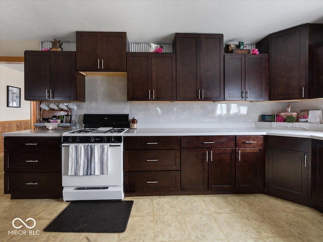 kitchen featuring white range with gas cooktop, dark brown cabinets, and a textured ceiling