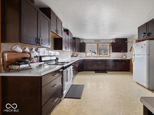 kitchen featuring sink, white appliances, dark brown cabinetry, tasteful backsplash, and a textured ceiling