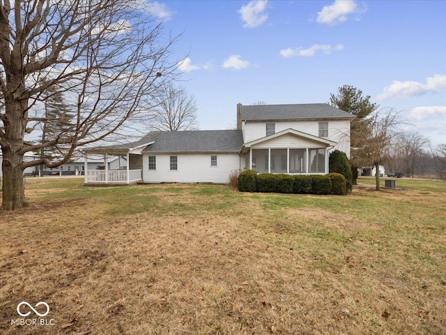 back of house featuring a sunroom and a lawn