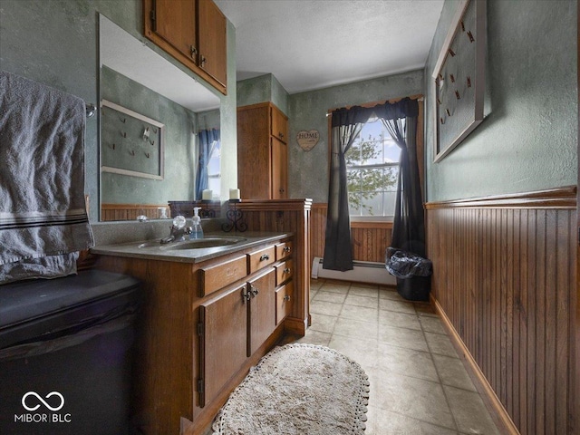 bathroom with wood walls, vanity, and a baseboard heating unit
