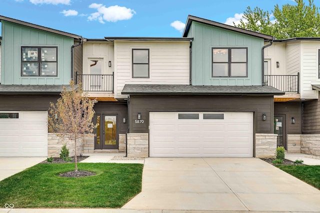 view of property with a garage, stone siding, driveway, and board and batten siding