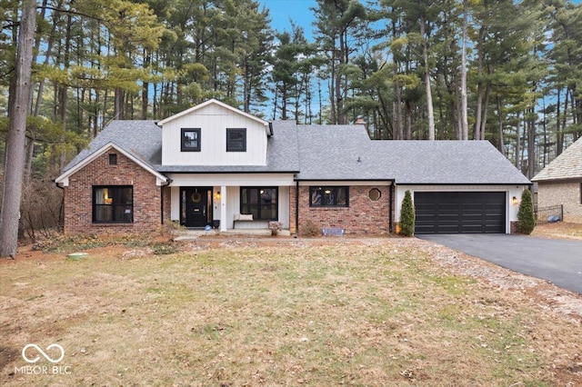 view of front of home with a garage, covered porch, and a front yard