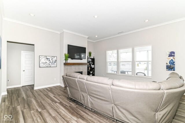 living room featuring baseboards, wood finished floors, a tile fireplace, and crown molding