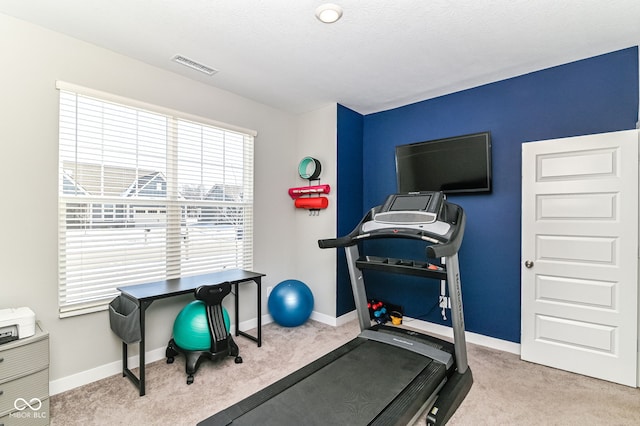 workout room with baseboards, visible vents, and light colored carpet