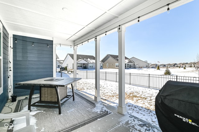 snow covered patio featuring a fenced backyard, a residential view, and grilling area