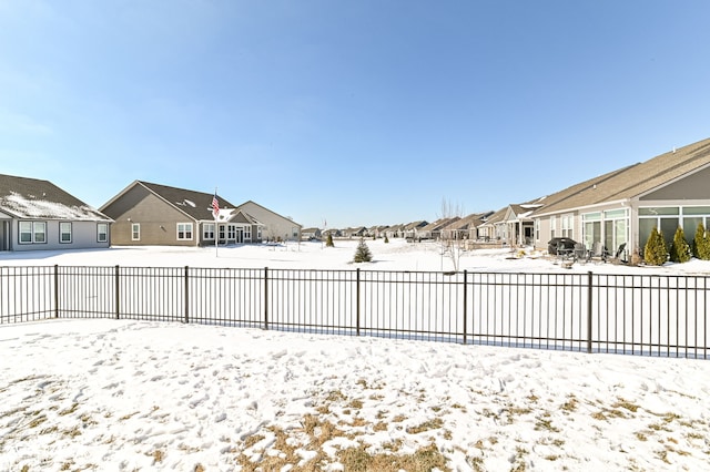 snowy yard with a residential view and fence