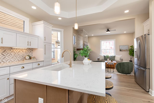 kitchen with white cabinetry, stainless steel fridge with ice dispenser, pendant lighting, and sink