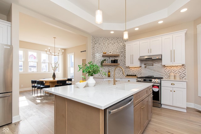 kitchen with sink, appliances with stainless steel finishes, white cabinetry, a tray ceiling, and light stone countertops