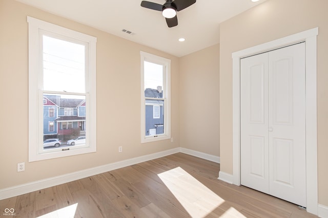 unfurnished bedroom with ceiling fan, light wood-type flooring, and a closet