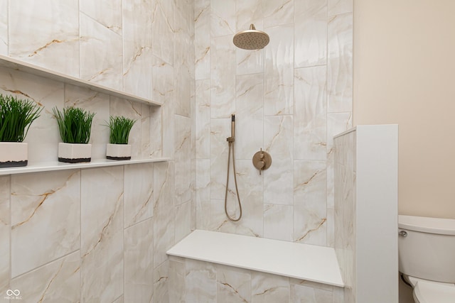 bathroom with a tile shower and toilet