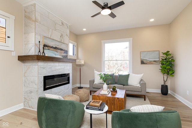 living room featuring a tile fireplace, ceiling fan, and light hardwood / wood-style flooring