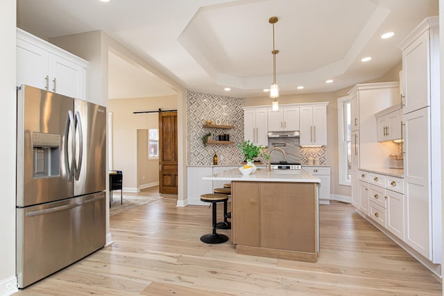 kitchen with white cabinetry, decorative light fixtures, stainless steel fridge with ice dispenser, a tray ceiling, and a barn door