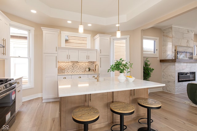 kitchen featuring white cabinetry, stainless steel gas range oven, and a tray ceiling