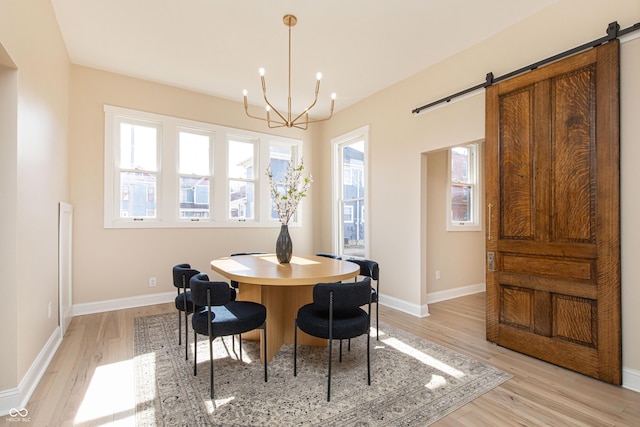 dining space featuring a barn door, a healthy amount of sunlight, and light wood-type flooring