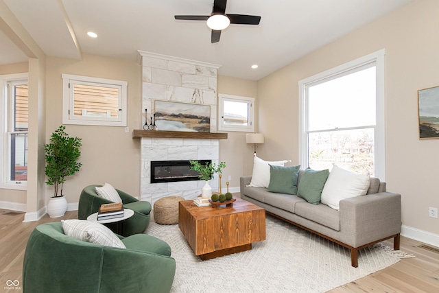 living room with ceiling fan, light hardwood / wood-style floors, and a tile fireplace