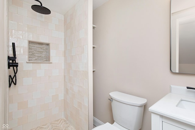 bathroom featuring vanity, a tile shower, and toilet