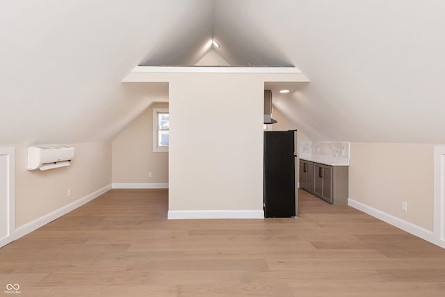 additional living space with lofted ceiling, light hardwood / wood-style floors, and an AC wall unit