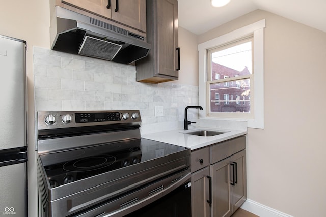 kitchen featuring sink, vaulted ceiling, dark brown cabinets, appliances with stainless steel finishes, and backsplash