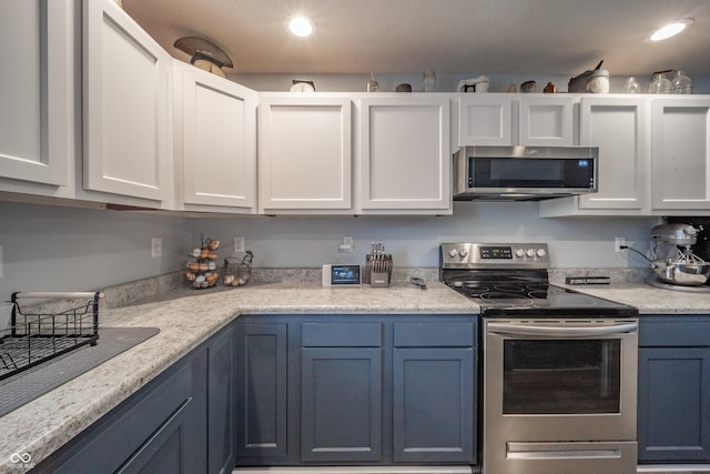 kitchen with white cabinetry, appliances with stainless steel finishes, and blue cabinetry